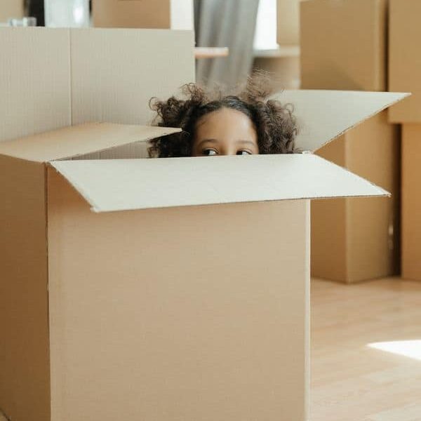 Petite fille dans un carton de déménagement
